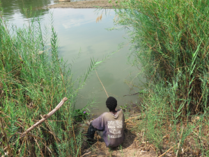 A boy fishes on the contaminated sediments at Hippo Pool
